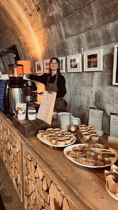 Lächelnde Dekhalu Barista an der Kaffeebar, ein süßes Buffet mit Gebäck im Vordergrund