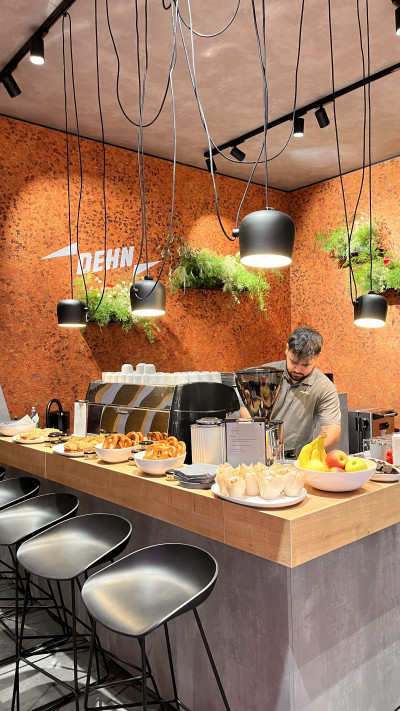 Dekhalu Barista bei der Arbeit an der Siebträgermaschine. Ein kleines Buffet aus Backwaren auf der Theke