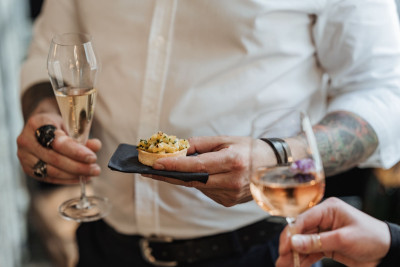 Gast mit Fingerfood Sektglas in der Hand