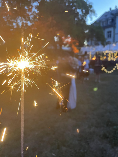Brennende Wunderkerze, im Hintergrund tanzt das Brautpaar im Freien