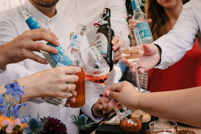 Gäste stoßen mit diversen Getränken miteinander an