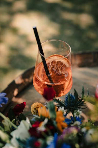 Ein Glas mit Aperolspritz zwischen Blumen
