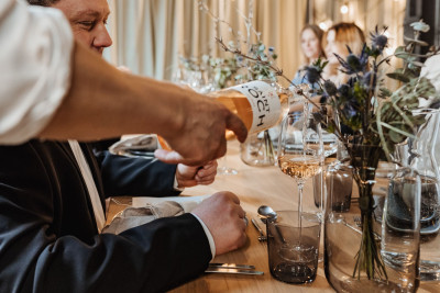 Servicekraft gießt Wein nach beim Dinner